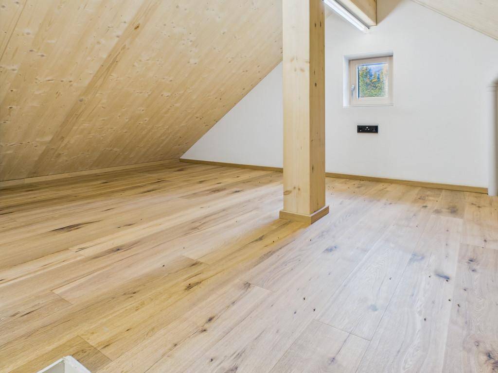 Geräumiger Dachbodenraum mit Holzboden, Dachschräge und Fenster, ideal für individuelle Nutzung.