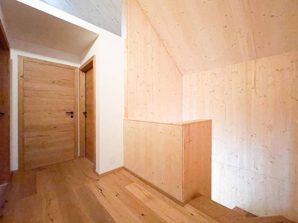 Heller Flur mit Holzboden und Holzverkleidung, der zu weiteren Zimmern führt.