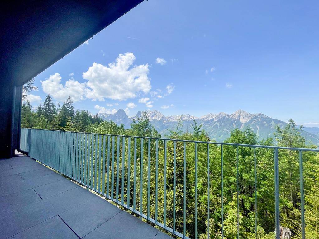 Balkon mit Fliesenboden und weitem Blick auf die grüne Berglandschaft unter blauem Himmel.