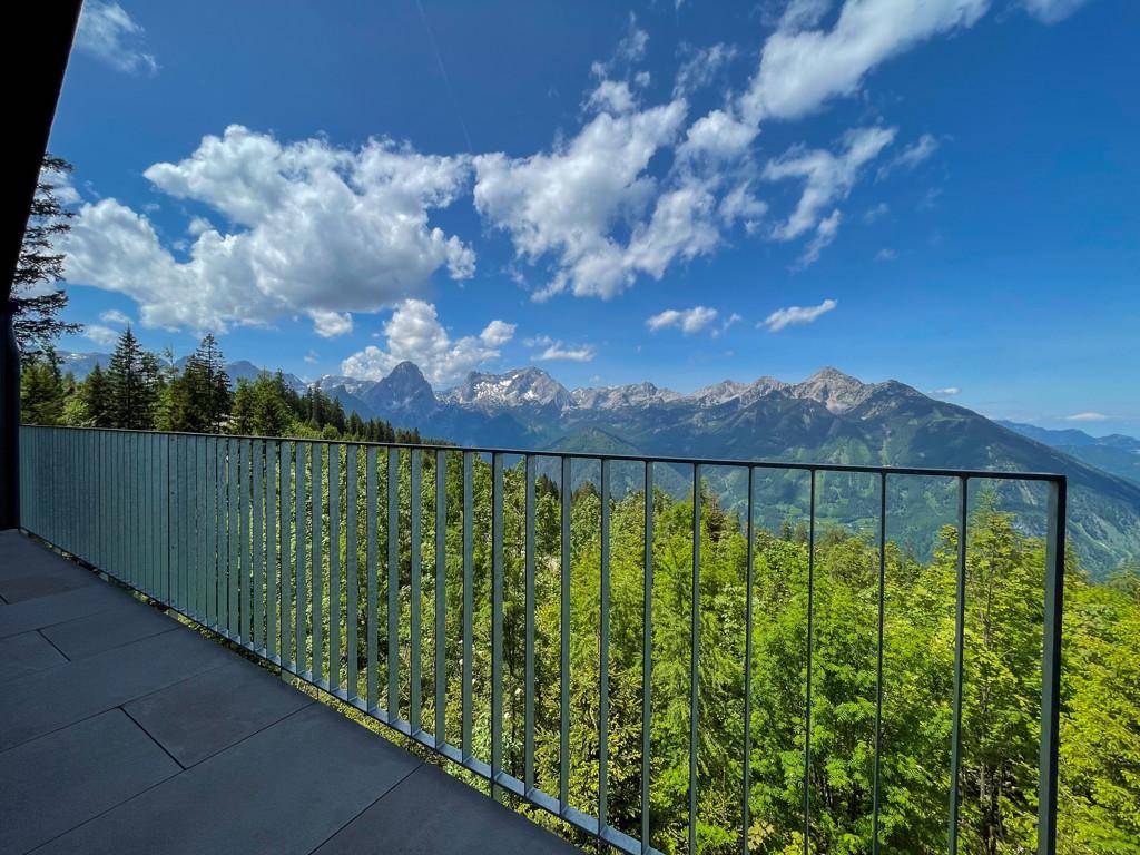 Balkon mit Fliesenboden und weitem Blick auf die grüne Berglandschaft unter blauem Himmel.