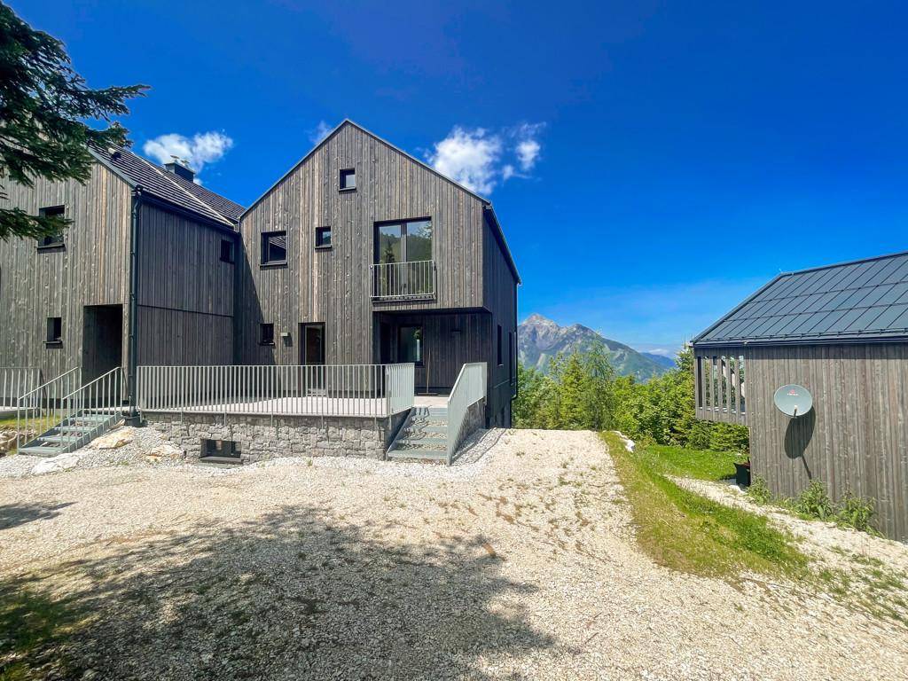 Moderne Holzhäuser in alpiner Umgebung mit Terrassen und Blick auf die umliegenden Berge.