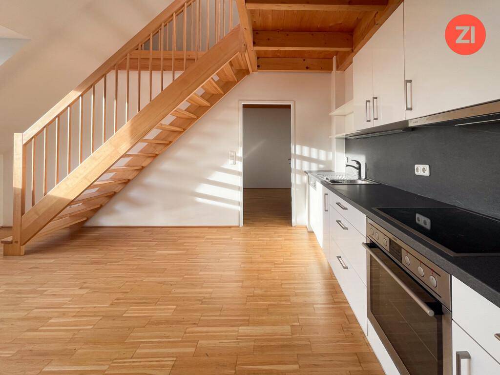 Moderne Einbauküche mit weißen Hochglanzschränken, dunkler Arbeitsplatte und integrierten Geräten.