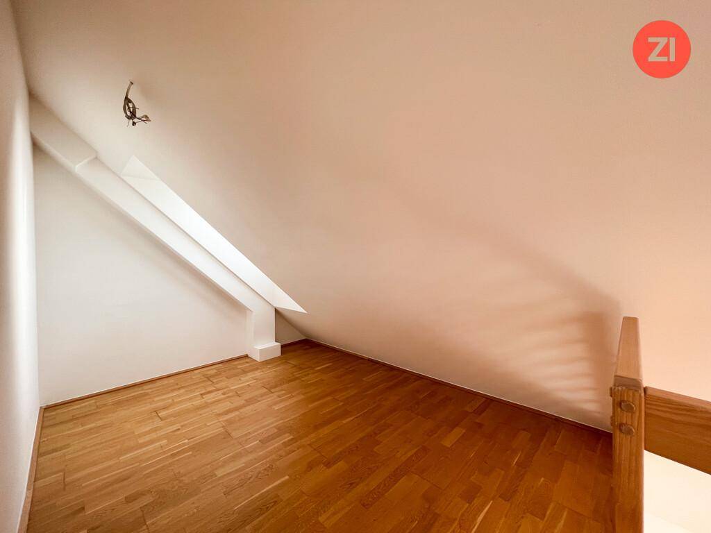 Helles Zimmer im Dachgeschoss mit Parkettboden und schrägen Wänden, ideal als Schlaf- oder Arbeitszimmer.