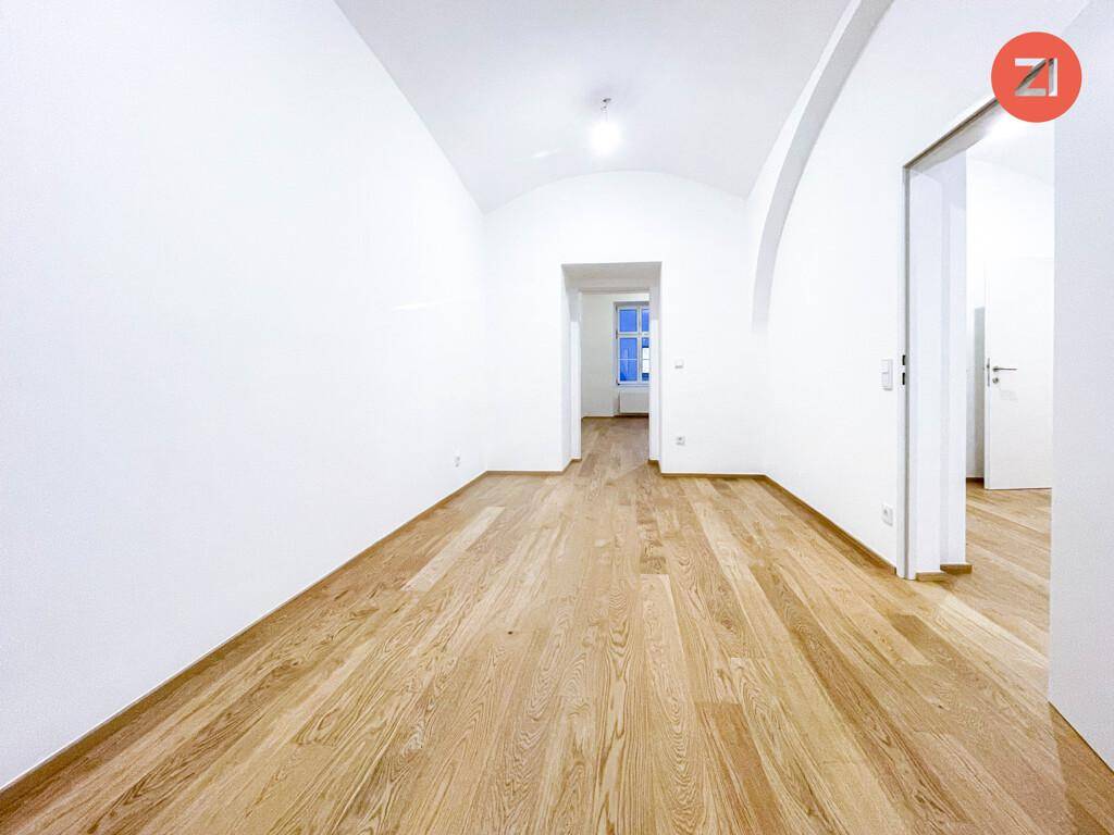 Großes, helles Zimmer mit Holzboden und gewölbter Decke, bietet vielseitige Nutzungsmöglichkeiten.