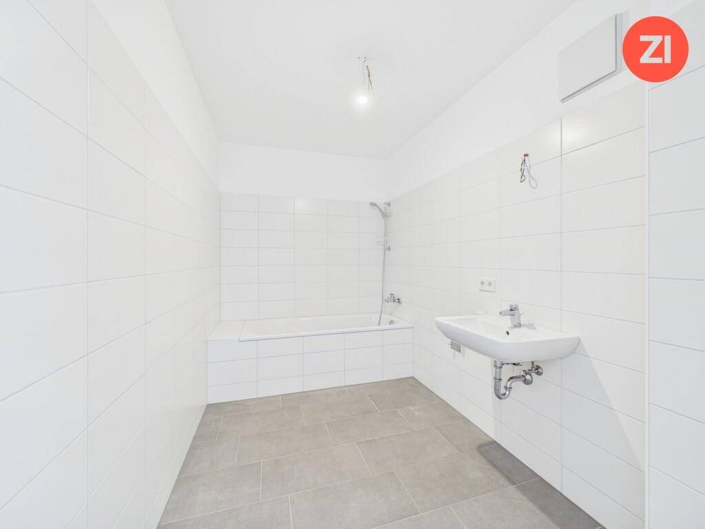Modernes Badezimmer mit weißen Wandfliesen, grauen Bodenfliesen, Badewanne und Waschbecken.