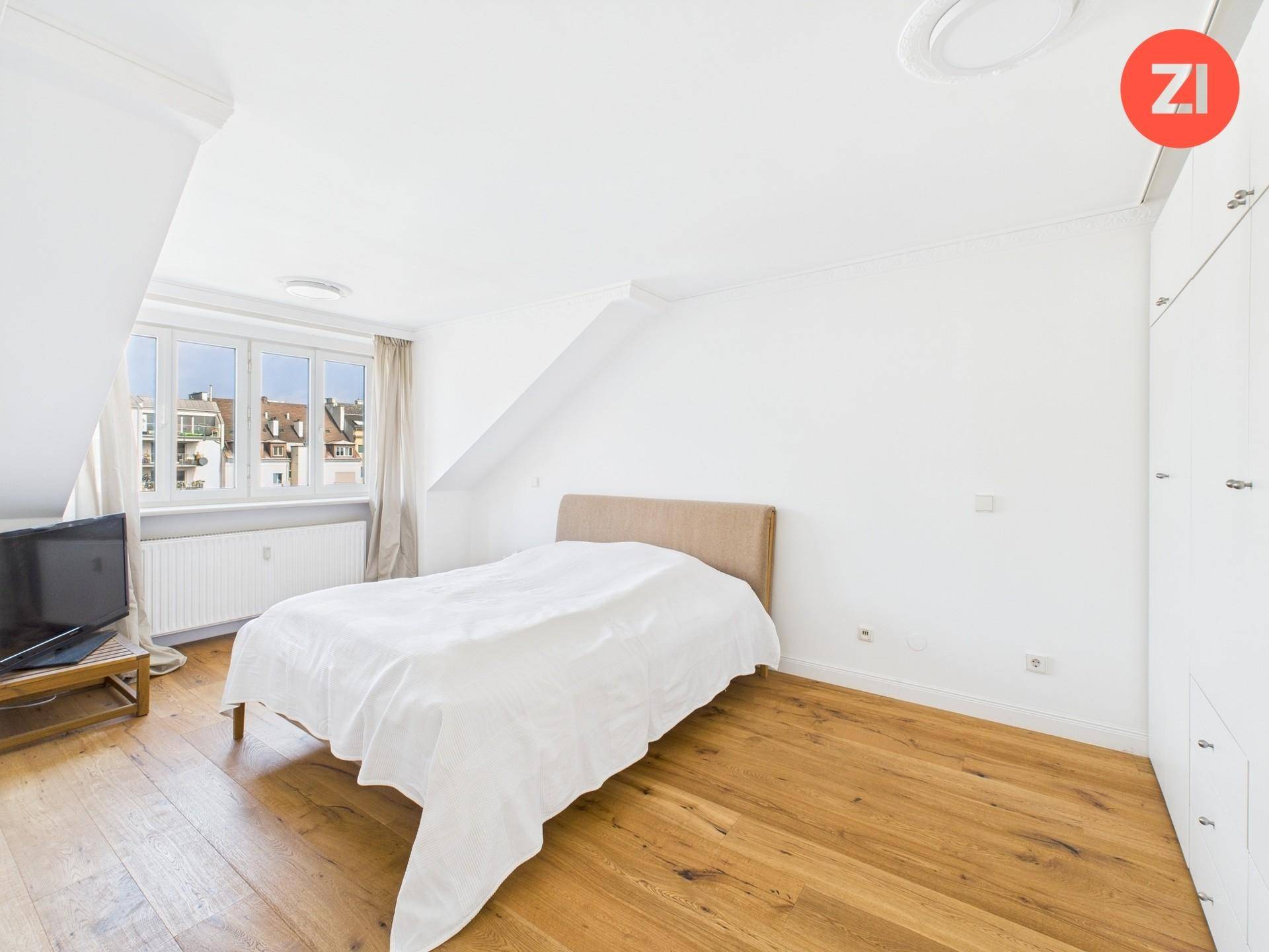 Helles Schlafzimmer mit Holzboden, großem Fenster und praktischen Einbauschränken unter der Dachschräge.