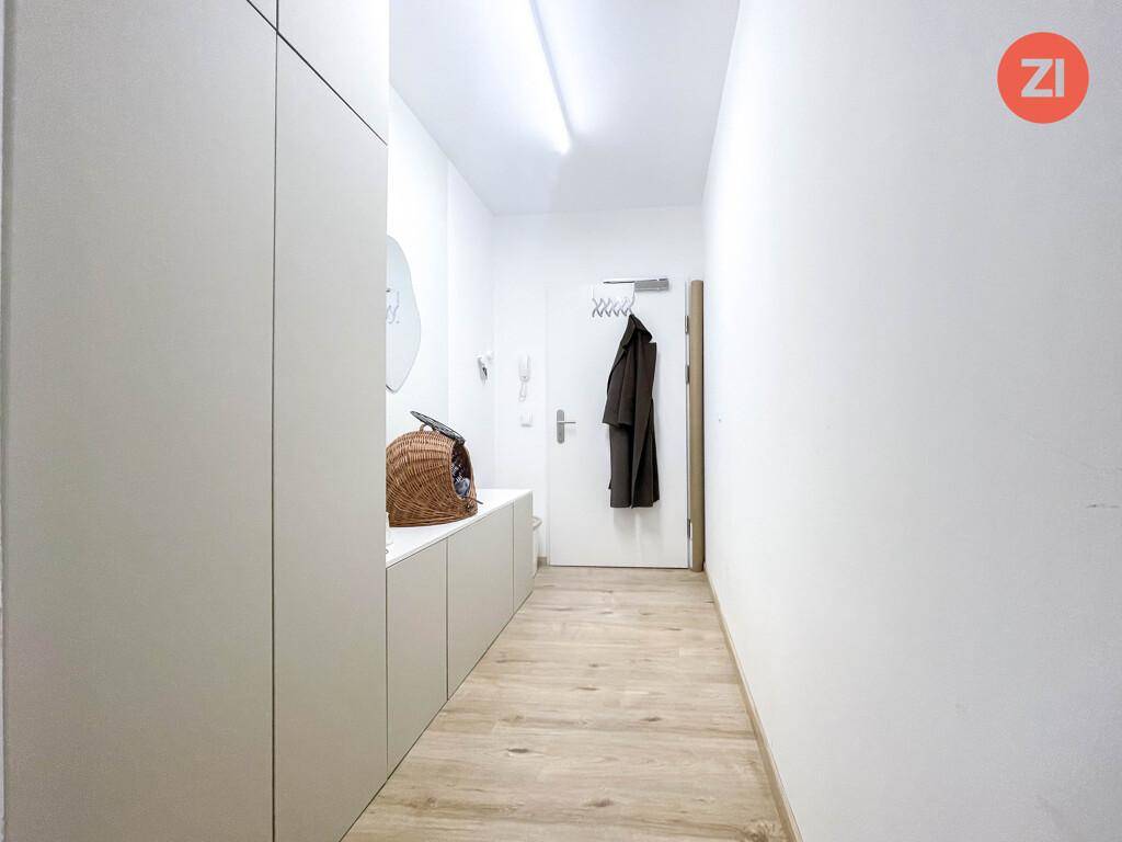 Heller Flur mit Holzboden, Einbauschränken und Garderobe am Eingangsbereich.