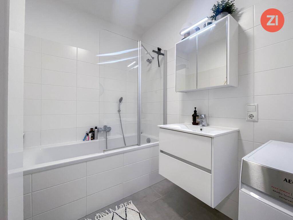 Modernes Badezimmer mit Badewanne, Duschabtrennung und weiß gefliesten Wänden.