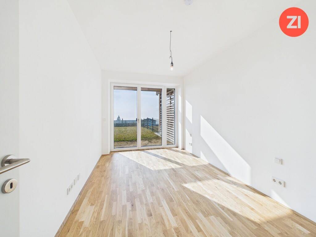Geräumiges Schlafzimmer mit Holzboden und großen Fenstern, die viel Tageslicht hereinlassen.