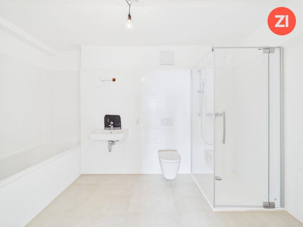 Modernes Badezimmer mit Badewanne, Duschkabine, WC und Waschbecken in hellen Farben.