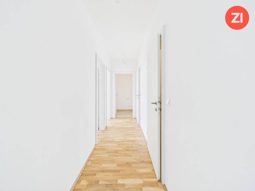 Langer, heller Flur mit Holzboden und mehreren Türen zu den angrenzenden Zimmern.