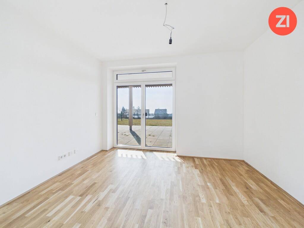 Lichtdurchflutetes Schlafzimmer mit Holzboden und direktem Zugang zum Außenbereich durch große Fenster.