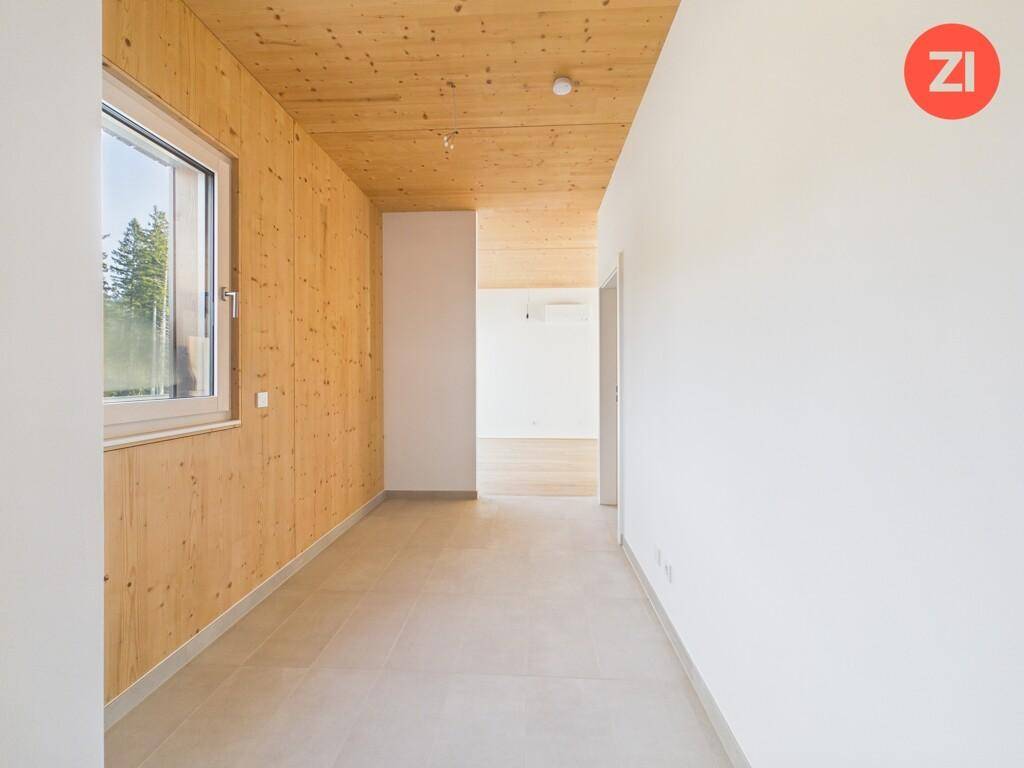 Heller Flur mit Fliesenboden und Holzwandverkleidung, der zu weiteren Räumen führt und Tageslicht bietet.