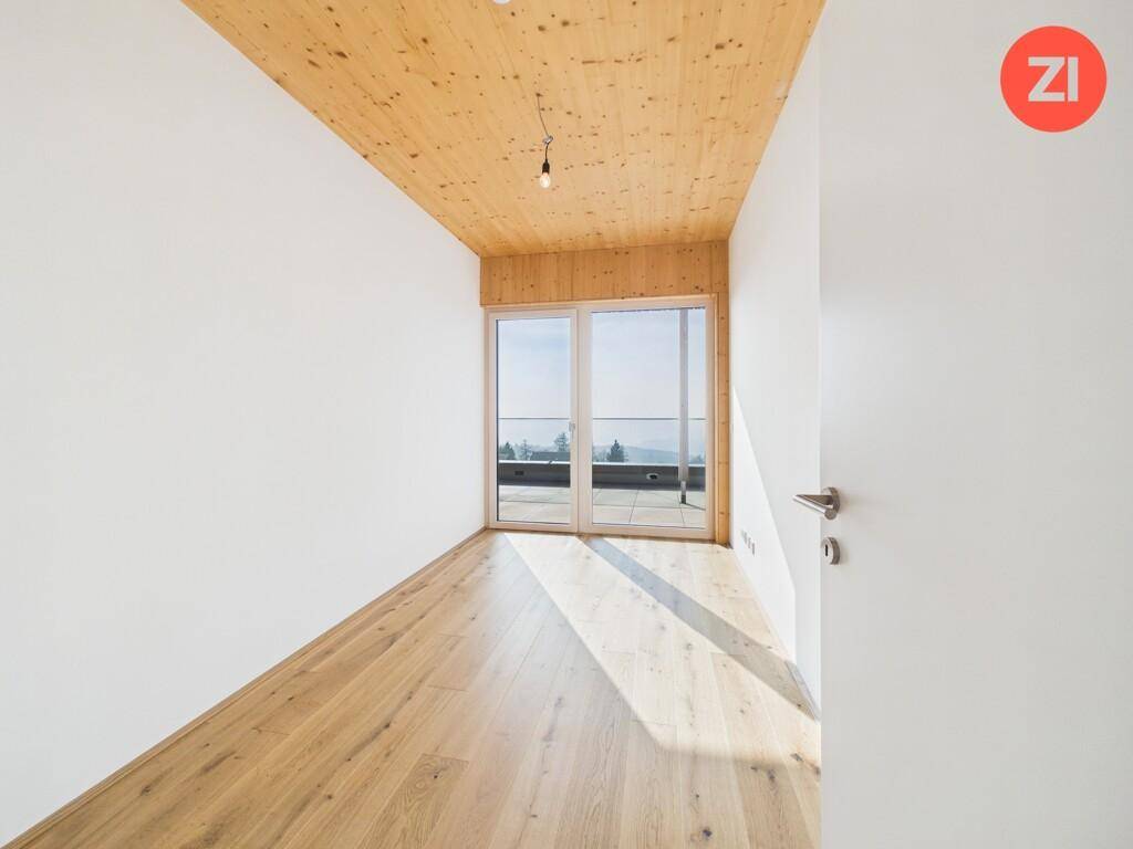 Helles Schlafzimmer mit Holzboden, Holzdecke und direktem Zugang zu einem Außenbereich mit Fernblick.