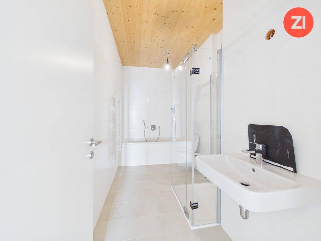 Modernes Badezimmer mit weißen Fliesen, begehbarer Dusche, Badewanne und Einzelwaschbecken.