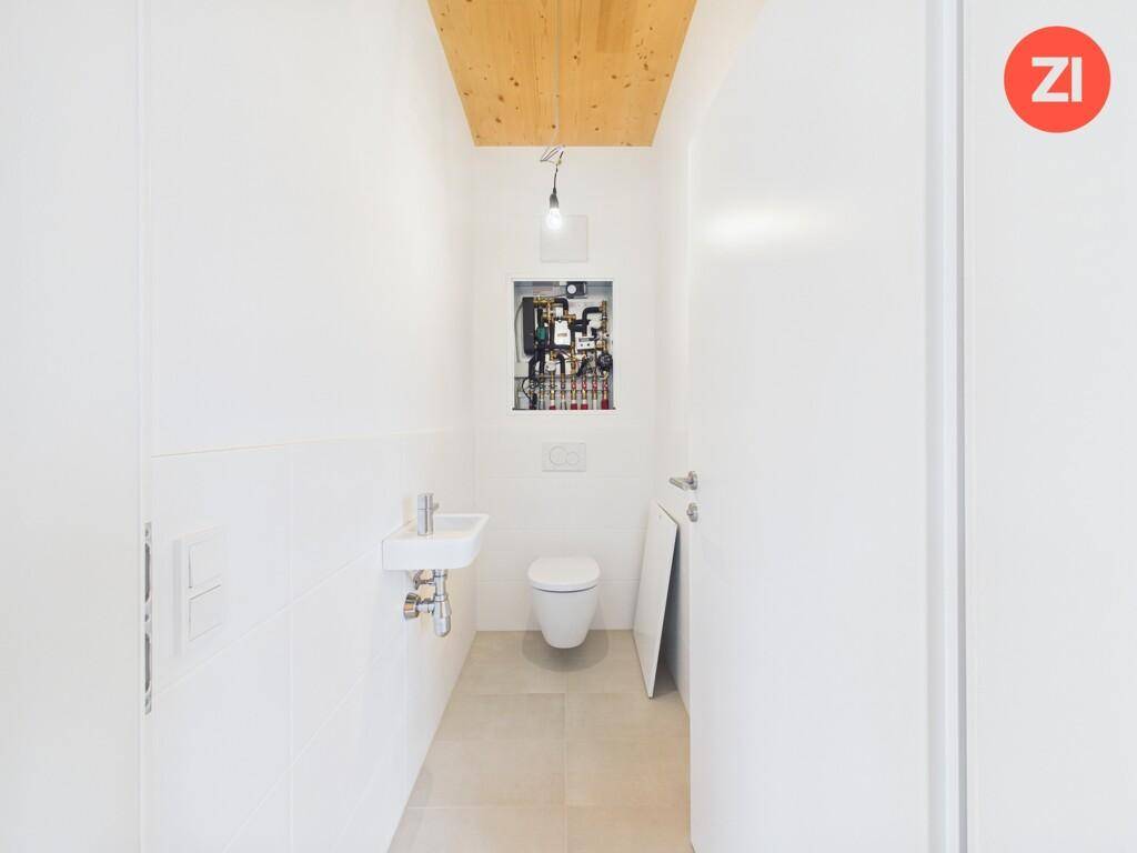 Funktionelles Gäste-WC mit wandhängender Toilette, kleinem Waschbecken und Fliesenboden.
