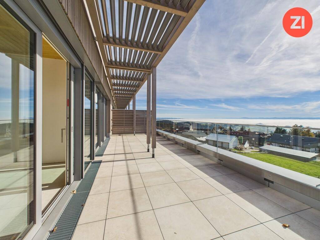 Großzügige Terrasse mit Pergola und Fliesenboden, die einen beeindruckenden Weitblick über die Landschaft bietet.