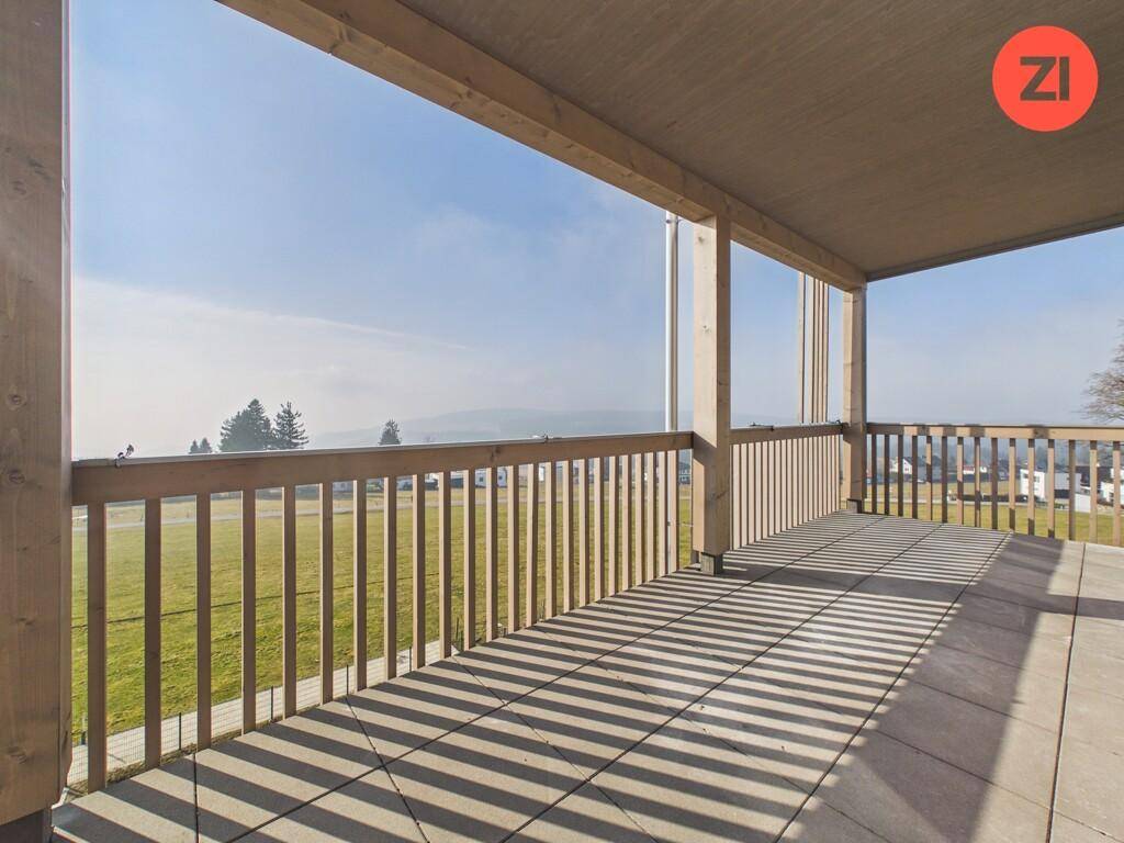 Große überdachte Terrasse mit Fliesenboden und weitem Blick über die Landschaft.