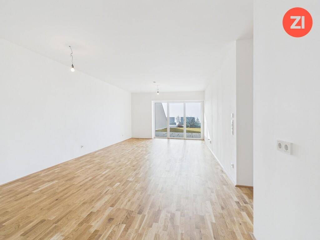 Geräumiges Wohnzimmer mit hellem Parkettboden und Zugang zur Terrasse.