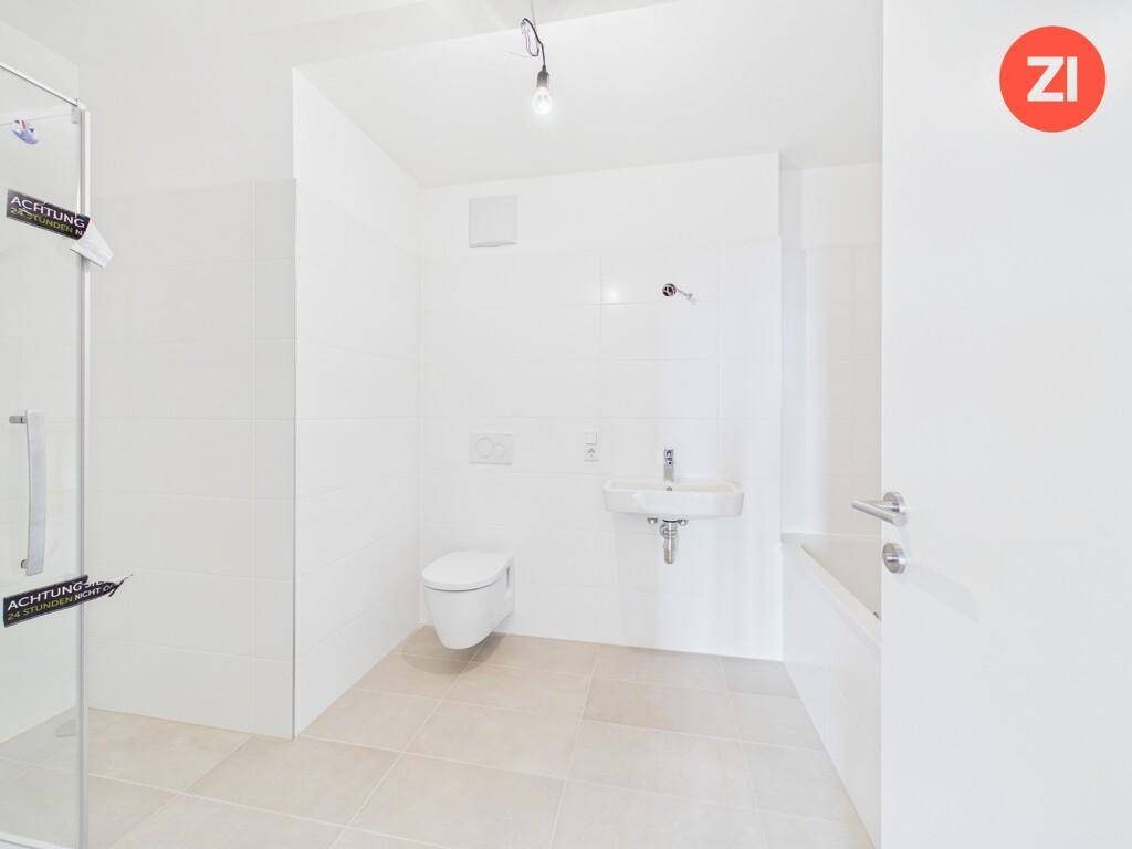 Modernes Badezimmer mit Dusche, WC und Waschbecken in hellen Fliesen.