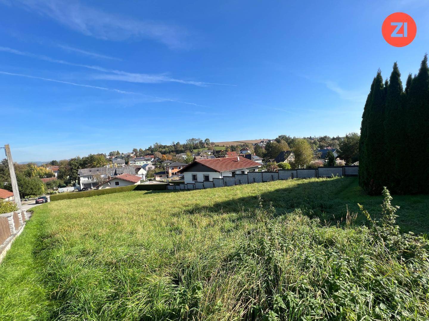 Großes unbebautes Grundstück mit Rasenfläche und Blick auf die Nachbarschaft unter klarem Himmel.