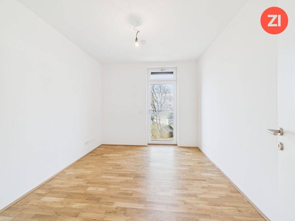 Gemütliches Schlafzimmer mit Holzboden und einem Fenster, das einen Blick nach draußen bietet.