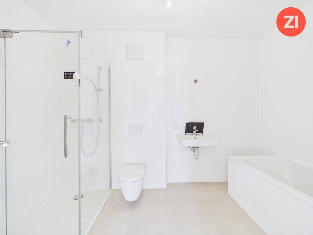 Modernes Badezimmer mit Dusche, Badewanne, WC und Waschbecken in hellen Farbtönen.