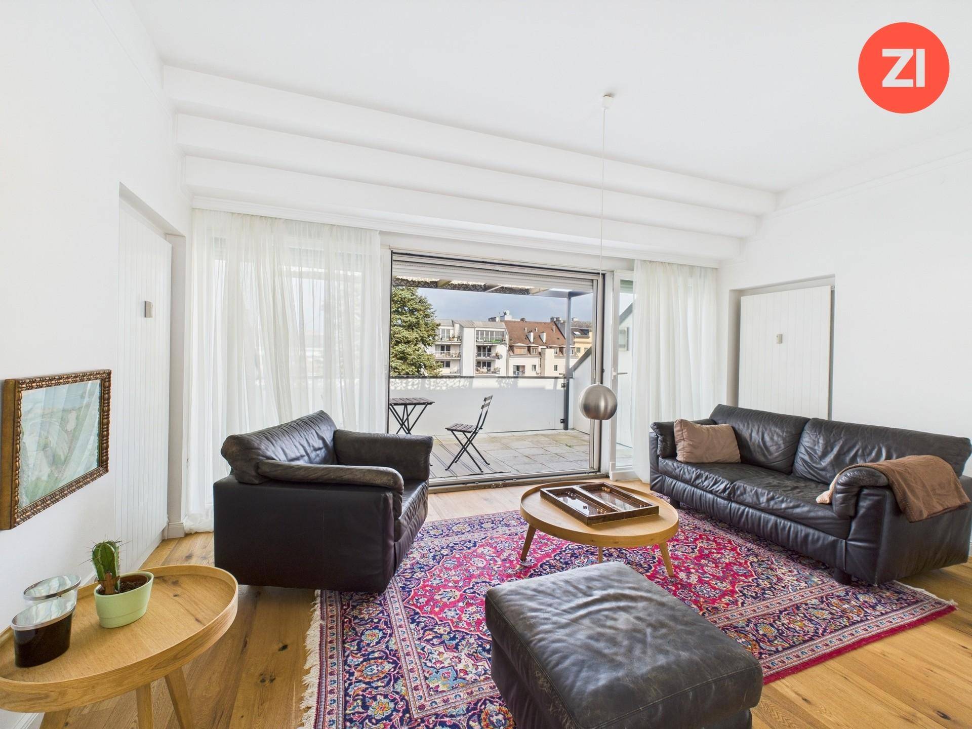 Heller Wohnraum mit Ledersofa, Holzboden und direktem Zugang zu einem sonnigen Balkon.