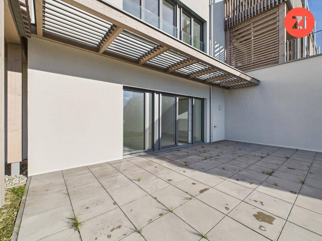 Große gepflasterte Terrasse mit Pergola und direktem Zugang zum Gebäude.