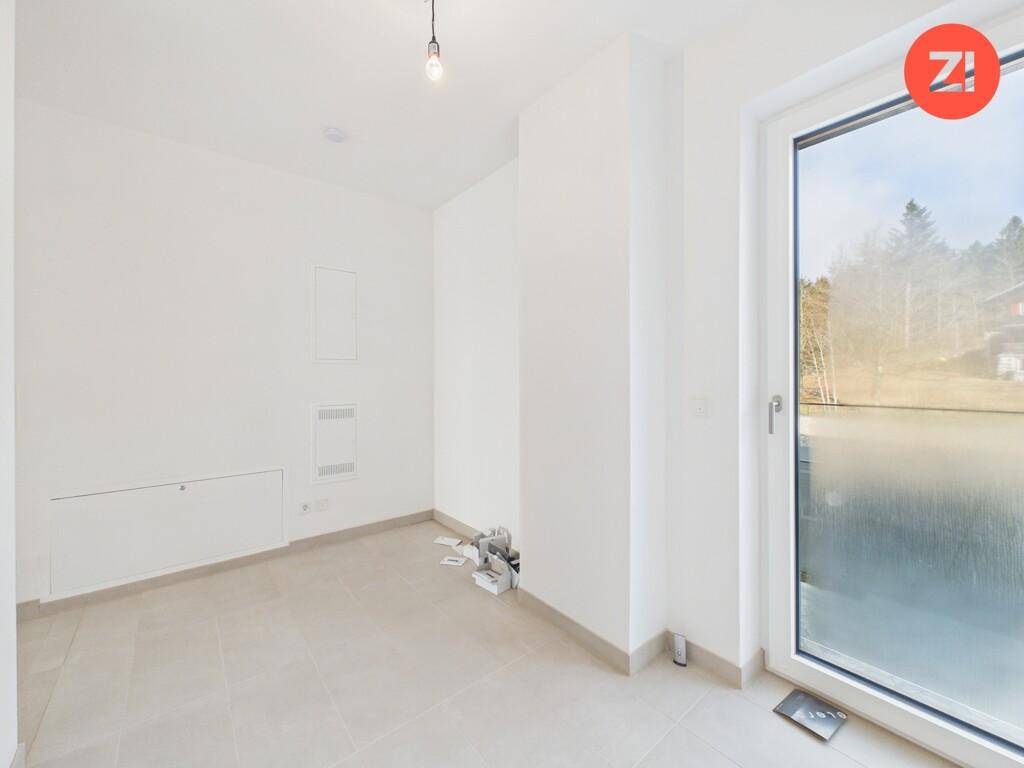 Kleiner Raum mit Fliesenboden und großem Fenster, ideal als Abstellraum oder Gästezimmer.