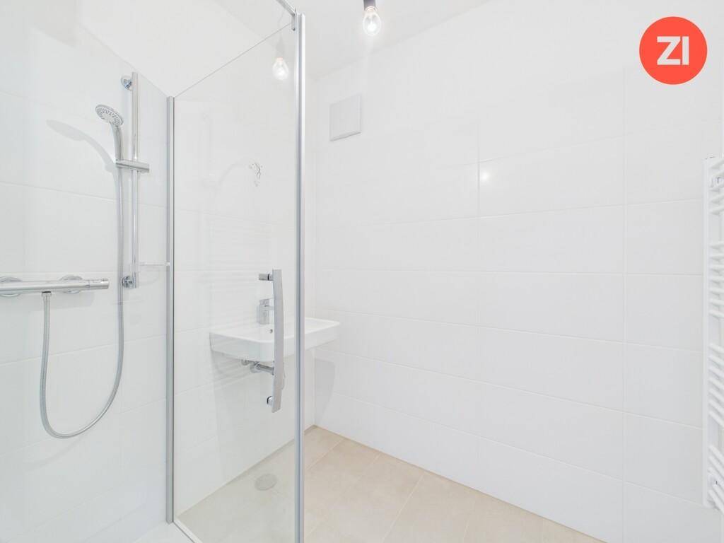 Modernes Badezimmer mit weiß gefliesten Wänden, ebenerdiger Dusche und Einzelwaschbecken.