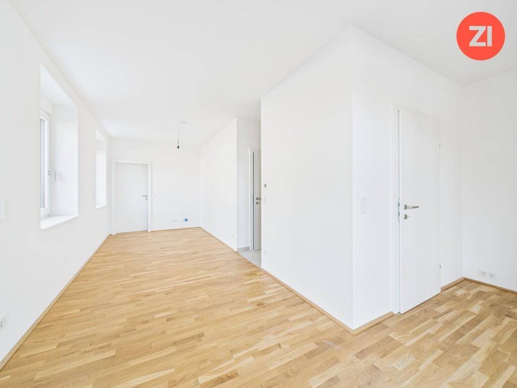 Geräumiger, unmöblierter Raum mit Holzboden und weißen Wänden, ideal für individuelle Gestaltung.