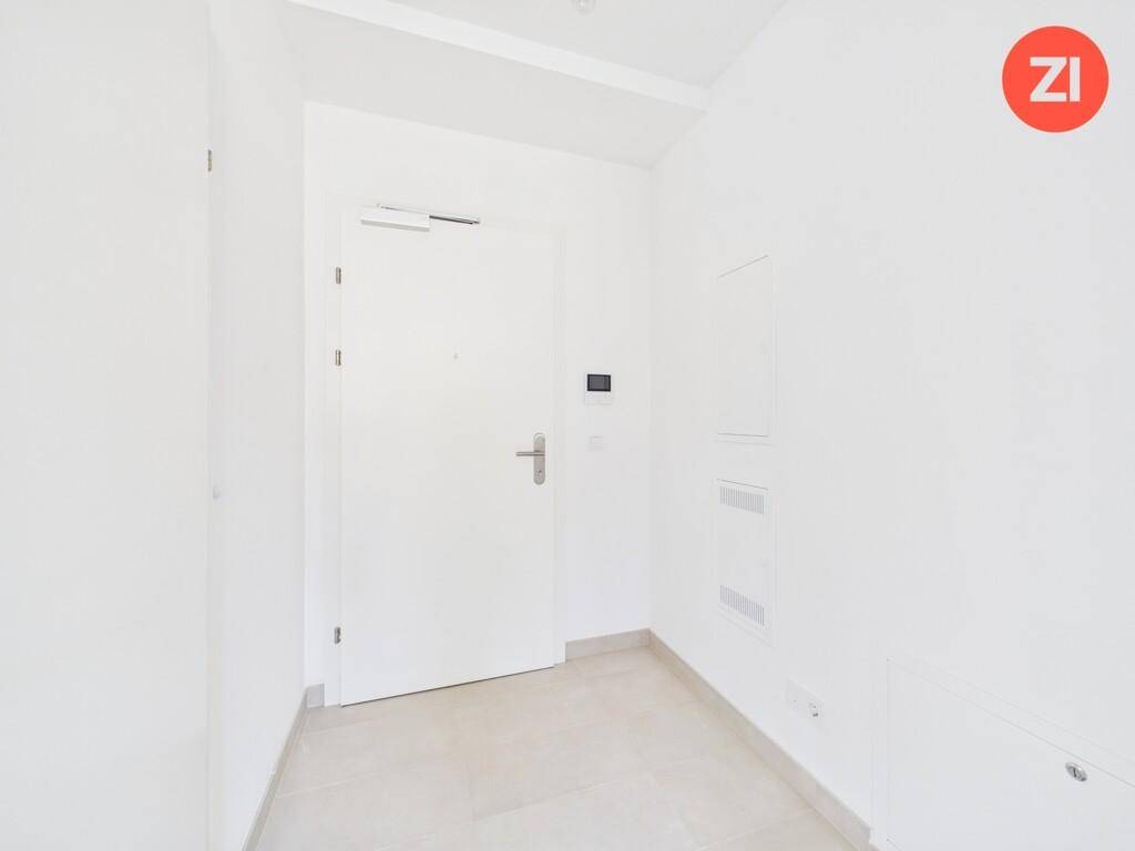 Heller Eingangsbereich mit Fliesenboden und weißer Tür, modern und funktional gestaltet.