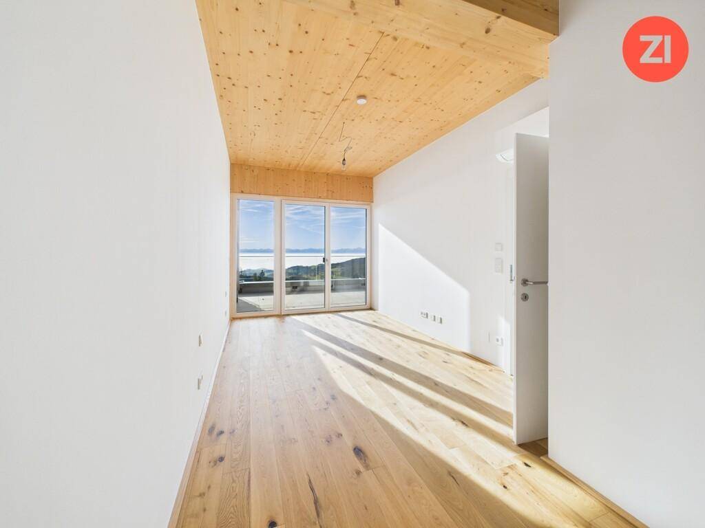 Heller, unmöblierter Raum mit Holzboden, Holzdecke und großen Fenstern mit Panoramablick.