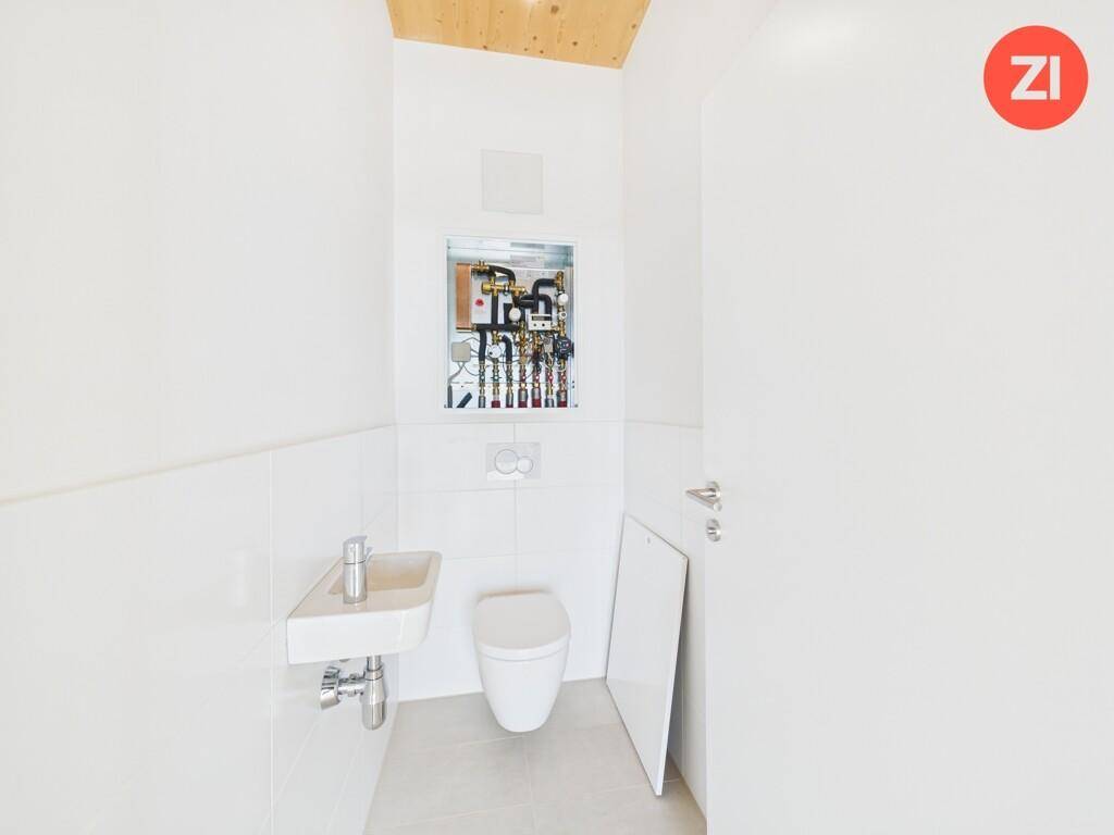 Modernes Gäste-WC mit wandhängender Toilette, kleinem Waschbecken und Technikzugang.