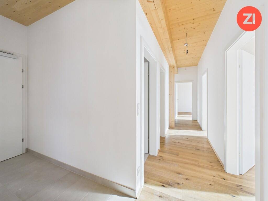 Heller Flur mit Holzboden und Holzdecke, der zu verschiedenen Räumen führt.