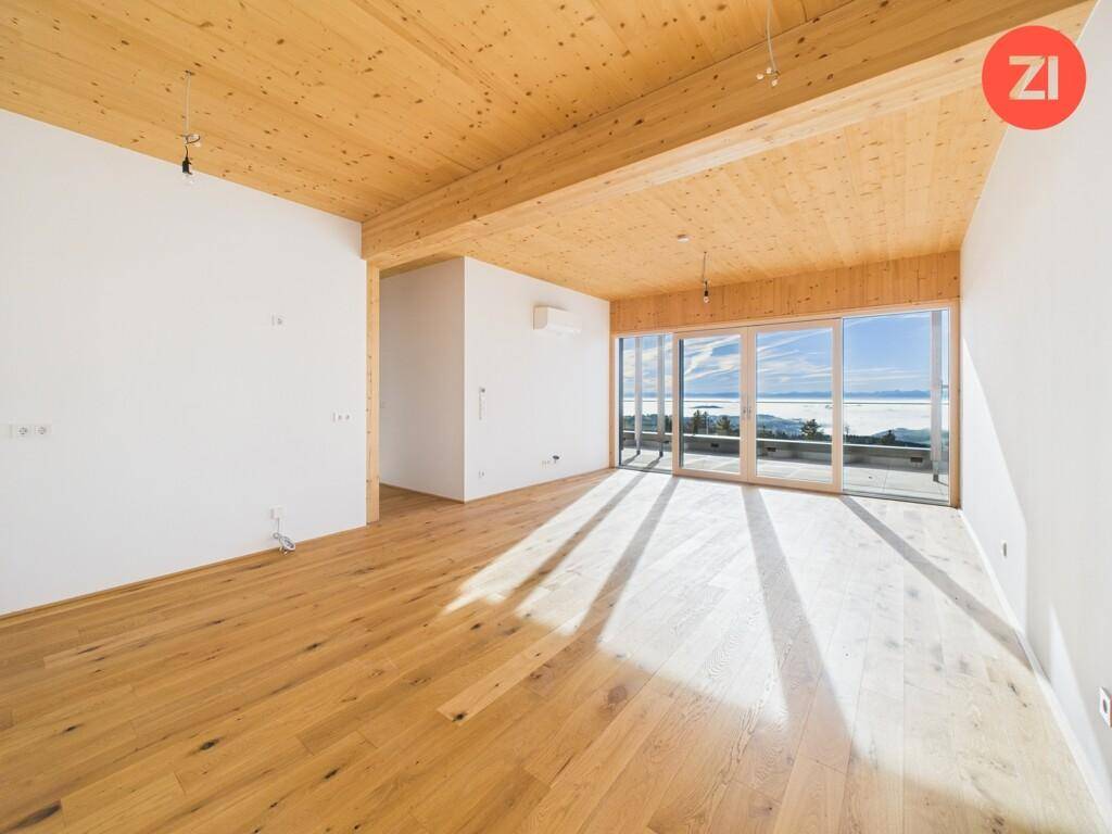 Geräumiger, unmöblierter Wohnbereich mit Holzboden, Holzdecke und großen Schiebetüren zum Außenbereich.