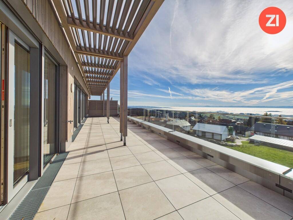 Moderne Terrasse mit Holzpergola, Fliesenboden und beeindruckendem Weitblick über die Umgebung.