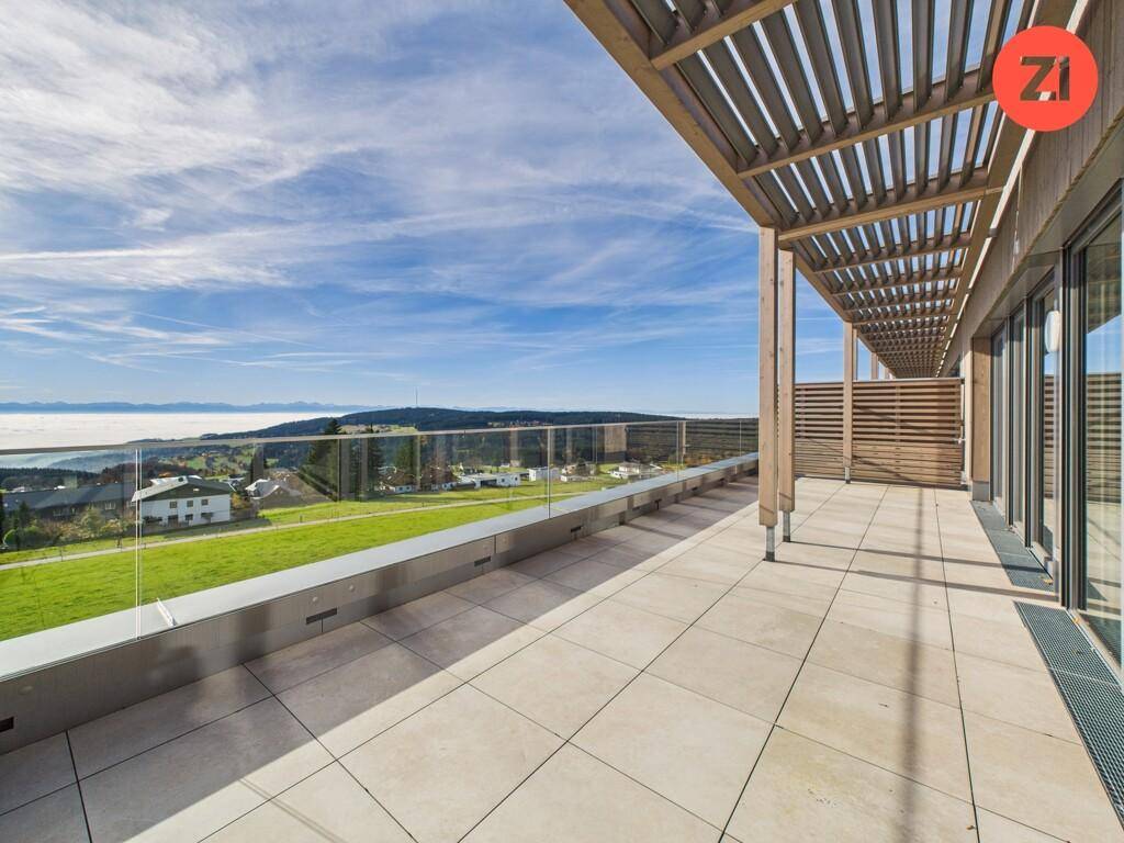 Große Dachterrasse mit Fliesenboden, Glasgeländer und atemberaubendem Weitblick über die Landschaft.