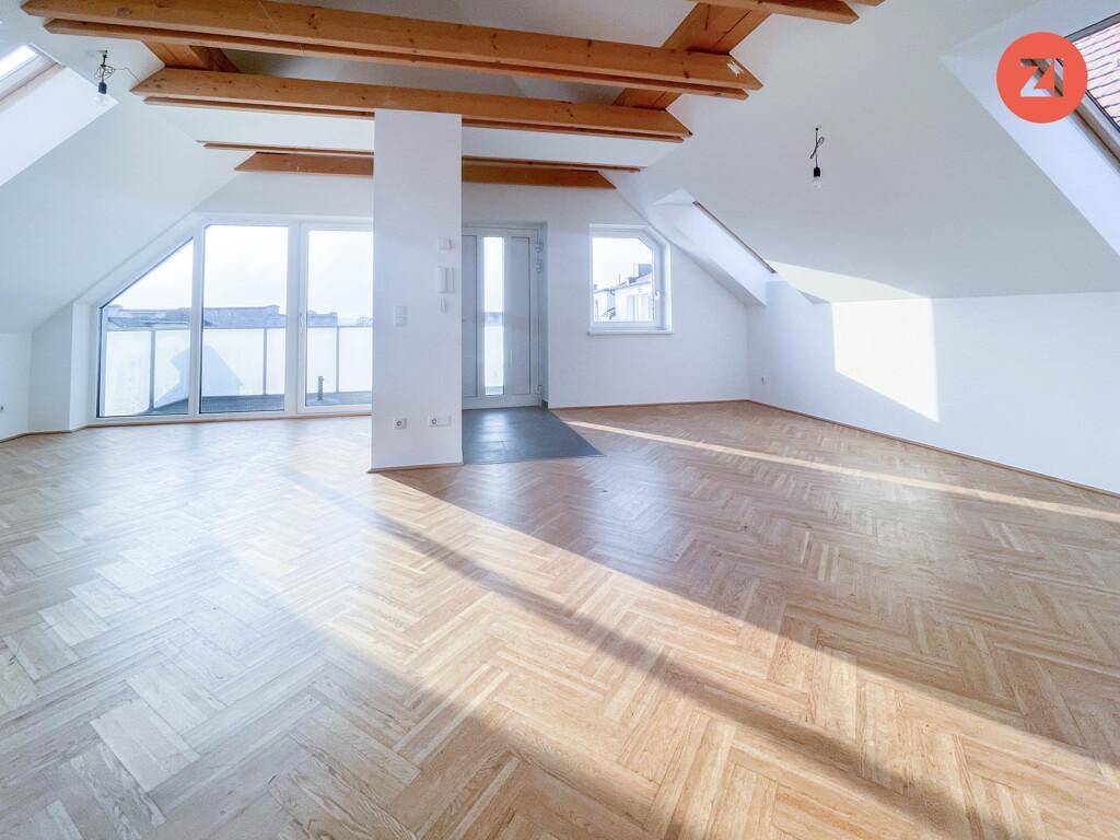 Geräumiger Dachbodenraum mit Holzbalken, Parkettboden und Zugang zu einem Balkon oder einer Terrasse.