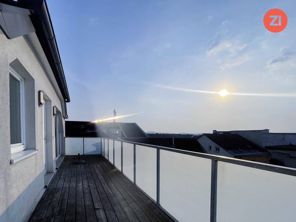 Große Dachterrasse mit Holzboden und Glasgeländer, bietet einen weiten Blick über die Dächer.