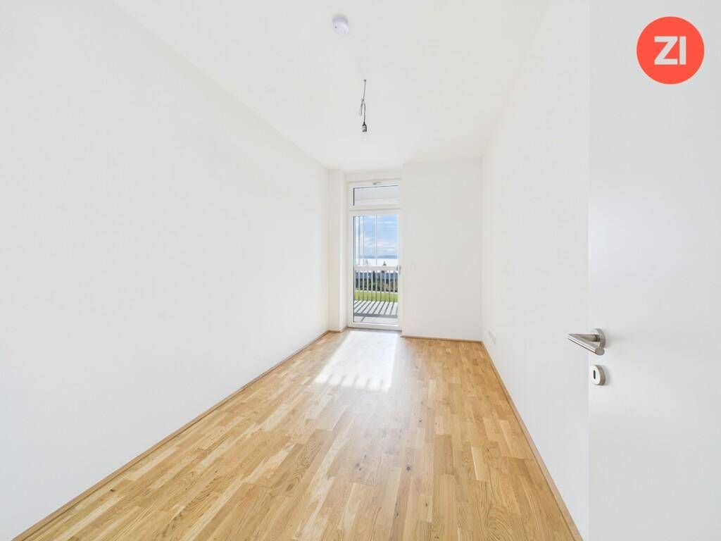 Helles Schlafzimmer mit Holzboden und Zugang zu einem Balkon oder einer kleinen Terrasse.