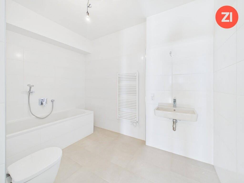 Modernes Badezimmer mit Badewanne, Waschbecken, beheiztem Handtuchhalter und weißen Fliesen.