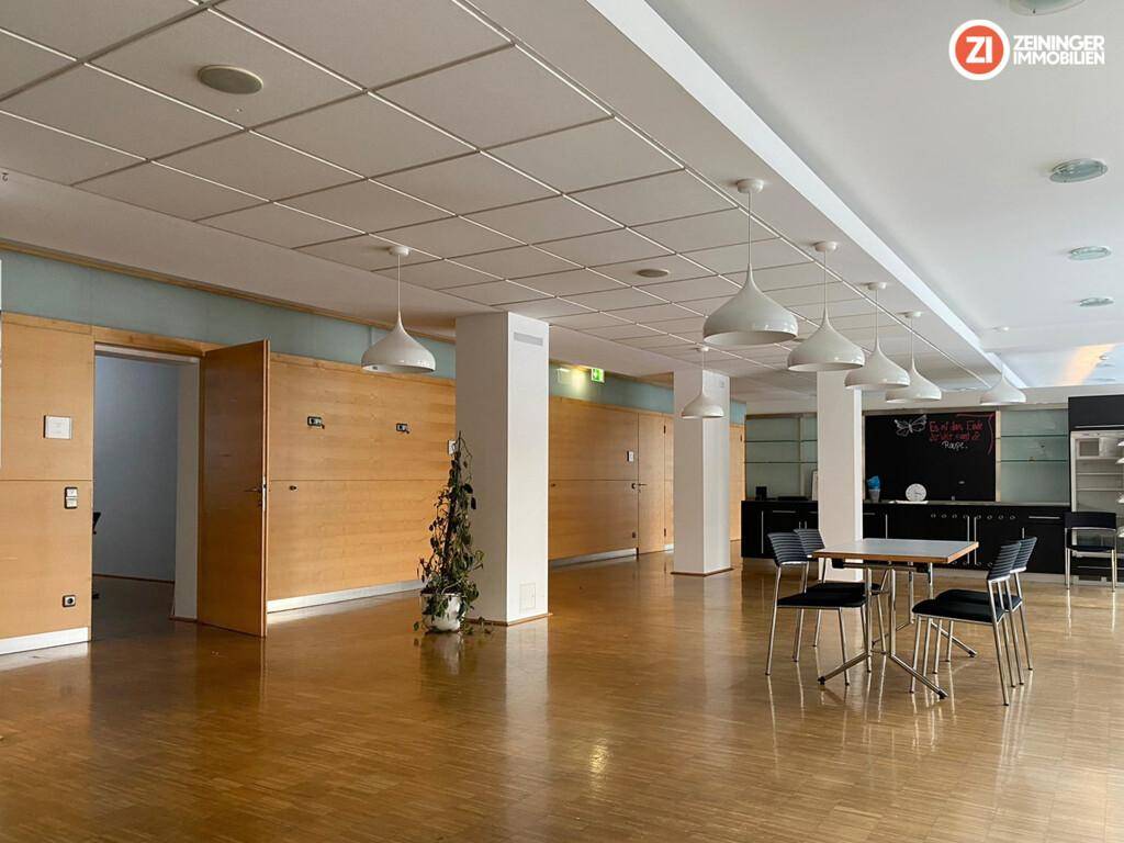 Geräumiger, offener Gewerberaum mit Holzverkleidungen, abgehängter Decke und modernen Pendelleuchten.