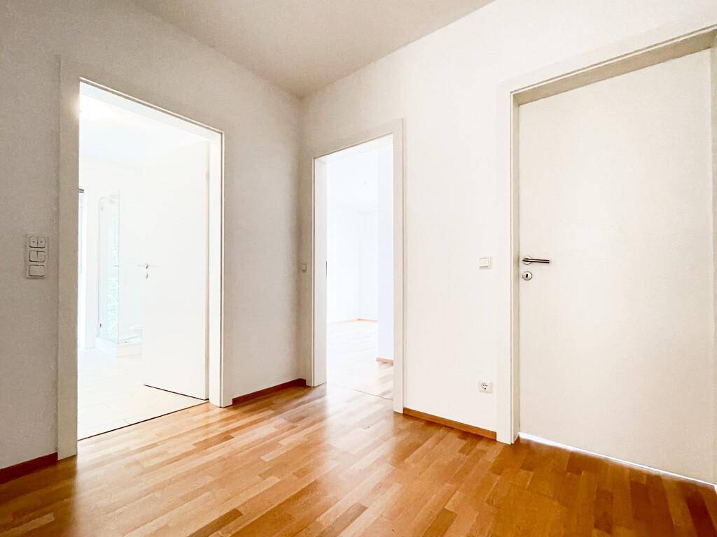 Heller Flur mit Parkettboden und mehreren weißen Türen, die zu den angrenzenden Wohnräumen führen.