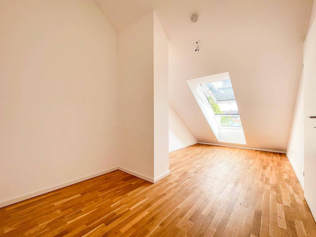 Helles Zimmer im Dachgeschoss mit Holzboden und einem großen Dachfenster.