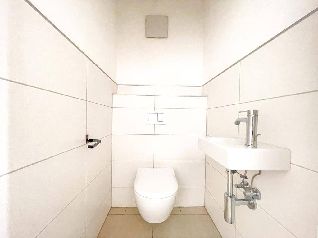 Kleines Gäste-WC mit wandhängendem WC und modernem Waschbecken.
