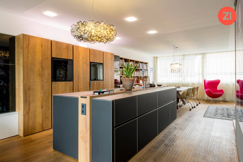 Moderne Küche mit großer Kücheninsel, Holzelementen und integrierten Geräten im offenen Wohnbereich.