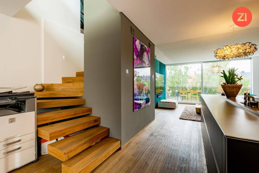 Heller Flur mit offener Holztreppe und Blick in den modernen Wohnbereich.