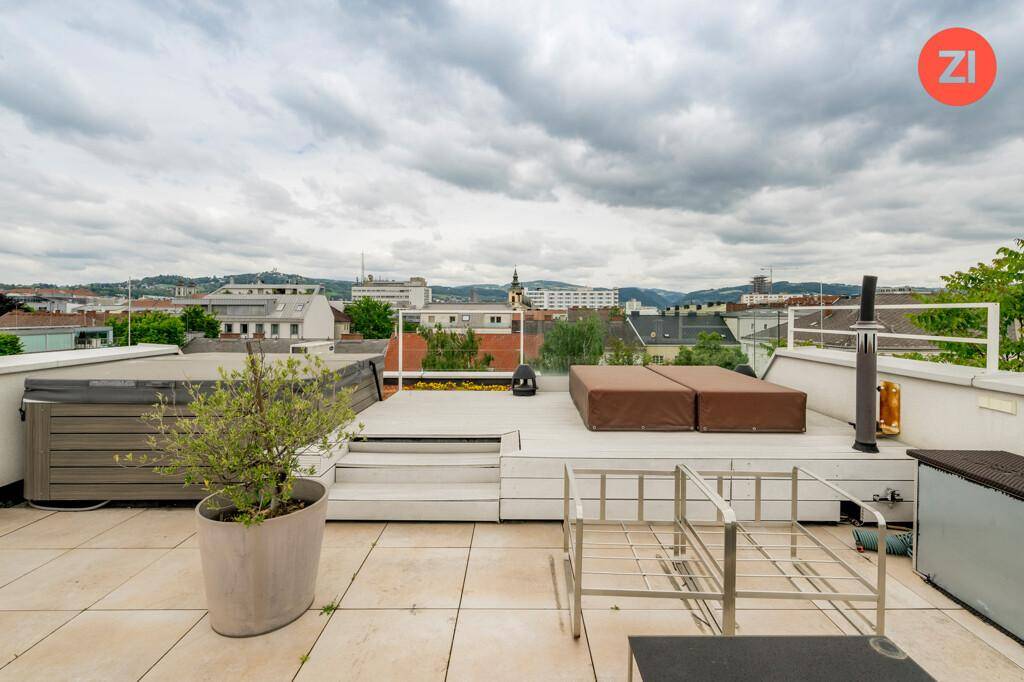 Weitläufige Dachterrasse mit Whirlpool, Liegeflächen und Panoramablick über die Stadt.